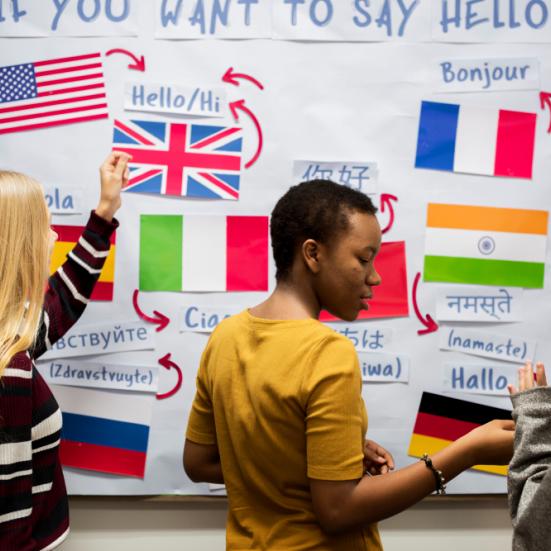 Tre kvinder står foran en tavle med en masse flag på, samt teksten "If you want to say hello".