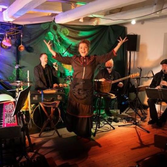 Stine Michel, der optræder med band foran en baggrund med lilla og grønt lys.