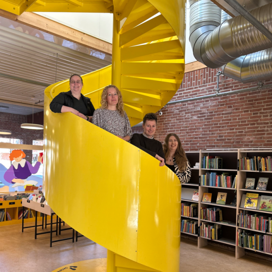 Bibliotekarerne Lisbeth, Christine, Rasmus og Fie på den gule vindeltrappe i børnebiblioteket.