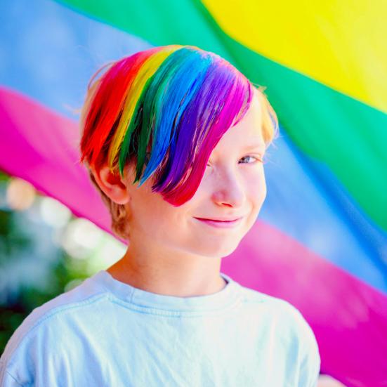 Barn med regnbuefarvet hår foran et Pride-flag.