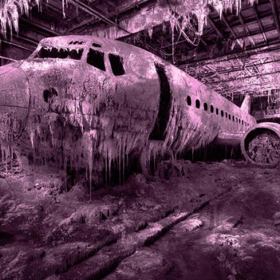 Billedkunst af Michael René Kristiansson, der forestiller et fly i forfald. Billedet er tonet lilla.