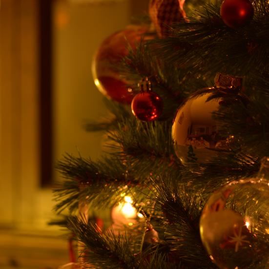 Juletræ med blanke julekugler og lyskæde på, i et blødt varmt lys.