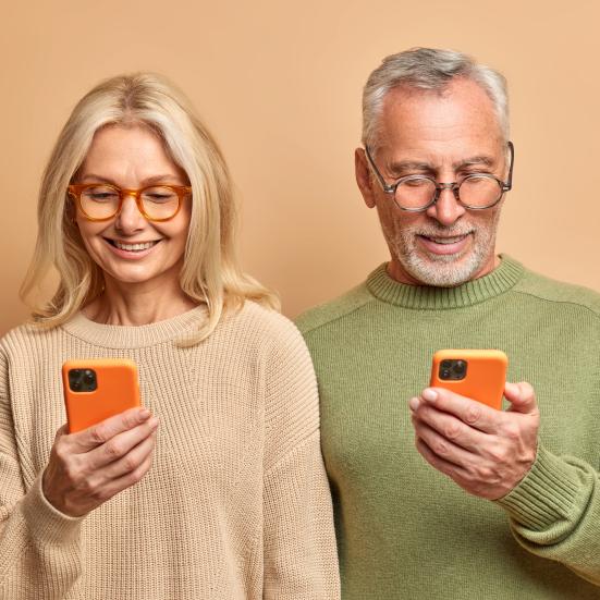 Et ældre par, der kigger på hver deres telefon.