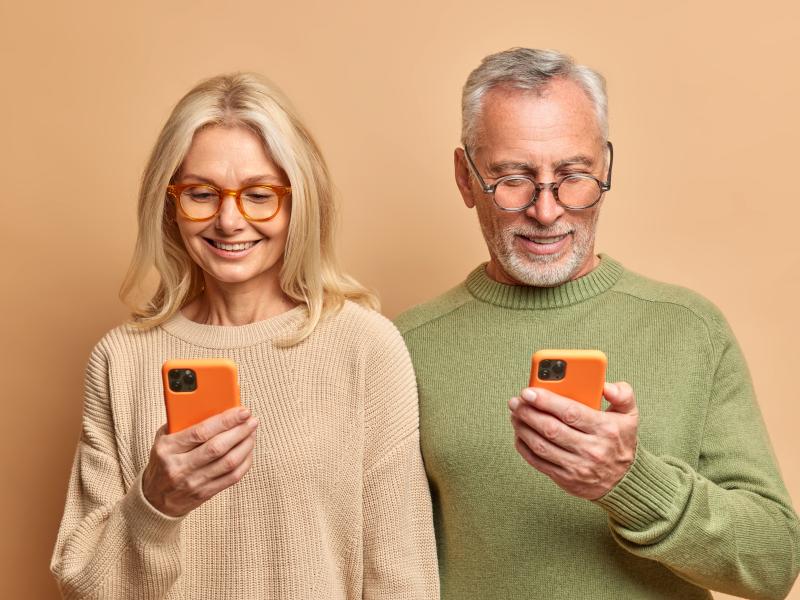 Et ældre par, der kigger på hver deres telefon.