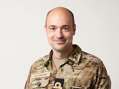 Portrætfoto af Anders Puck Jensen, iført militæruniform på hvid baggrund.
