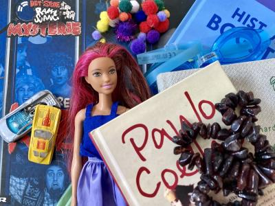 Foto af ting fra loppemarked, heriblandt en Barbie-dukke, en bog, et smykke og forskelligt nips.