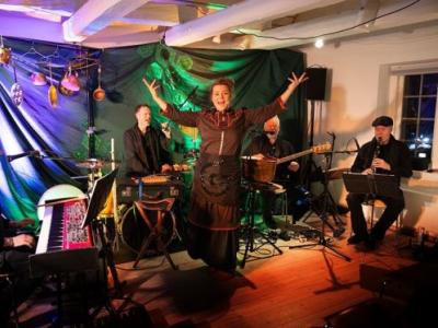 Stine Michel, der optræder med band foran en baggrund med lilla og grønt lys.