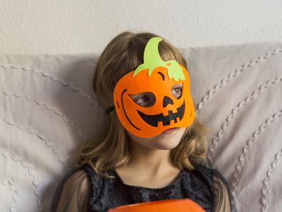 Barn med en filtmaske på, der forestiller et græskar.