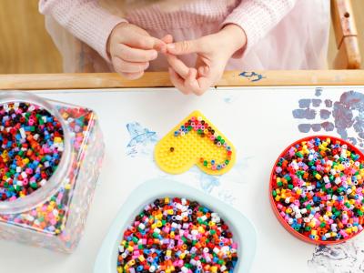 Et barn, der er ved at lave en perleplade formet som et hjerte.