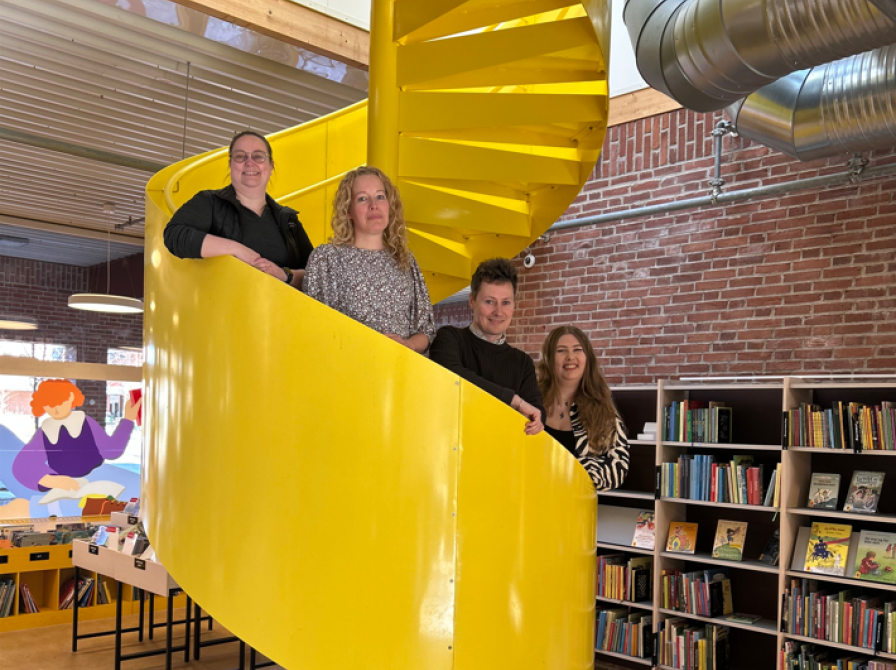 Bibliotekarerne Lisbeth, Christine, Rasmus og Fie på den gule vindeltrappe i børnebiblioteket.