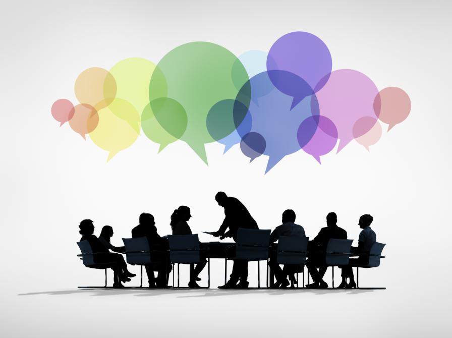 Grafik med mennesker om et bord, med farverige talebobler ovenover.