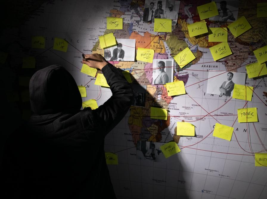 Opslagstavle med post-its, kort og snore. En person står med ryggen vendt mod kameraet, halvt i skygge.